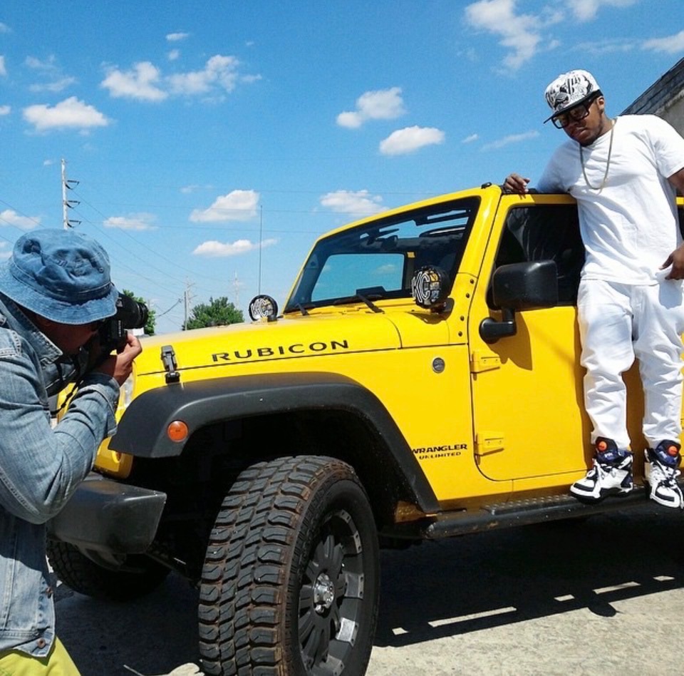 A photographer working with a subject beside a yellow Jeep on location