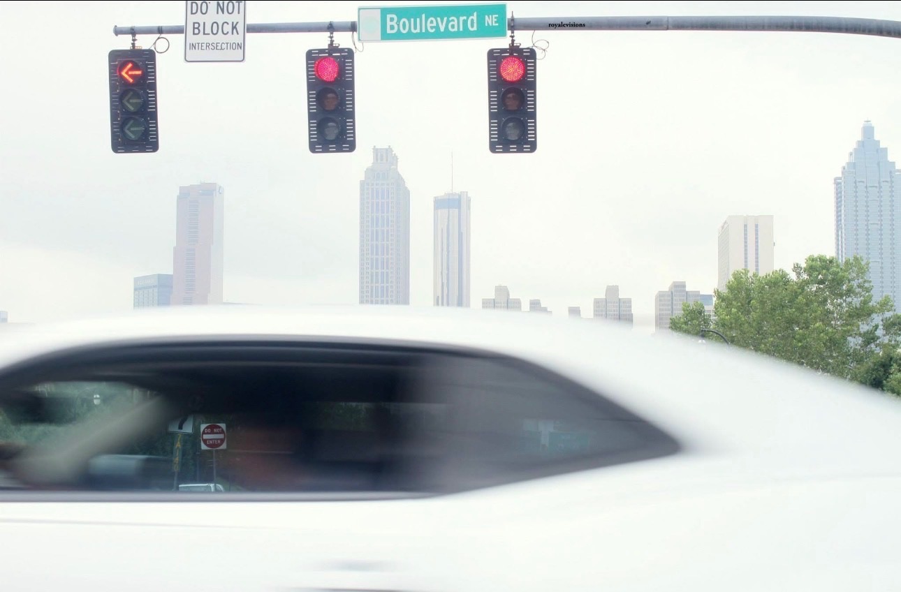 A moving white car crossing an Atlanta skyline view at Boulevard Northeast