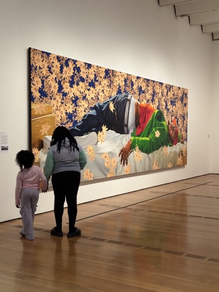 An adult and child standing before a large painting in a gallery