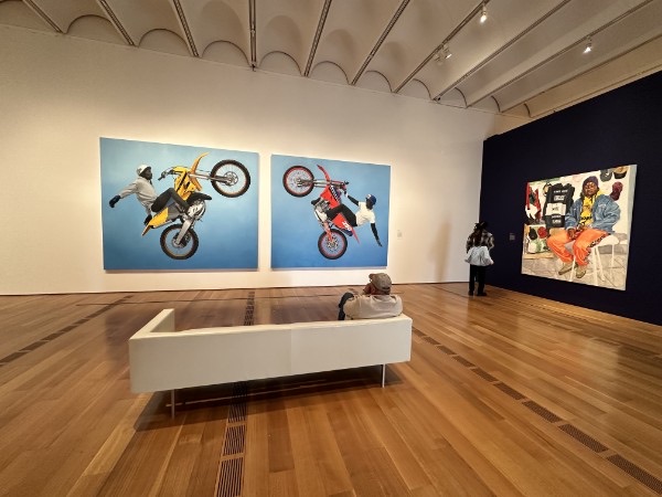 Visitors viewing large contemporary paintings in a bright art gallery