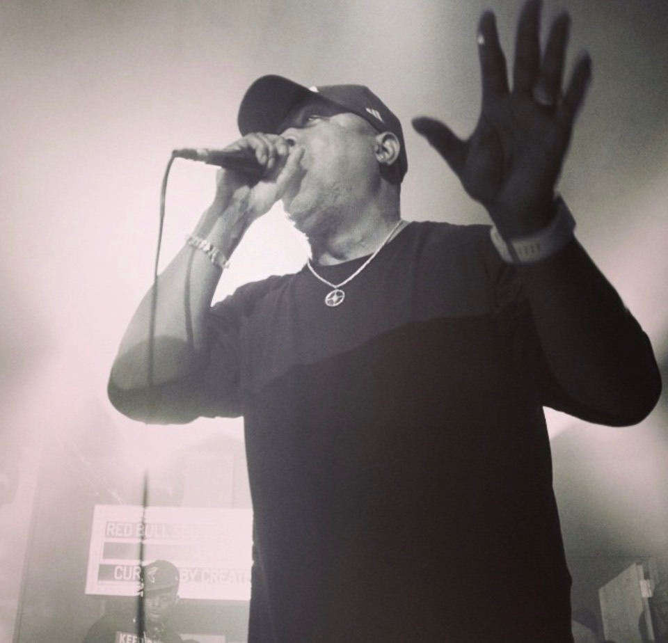 Black-and-white photograph of a vocalist performing through stage light and haze